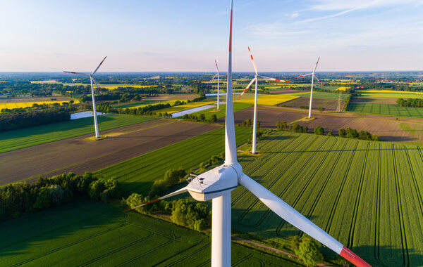 Windkraftanlagen auf einer grünen Wiese unter einem sonnigen Himmel.