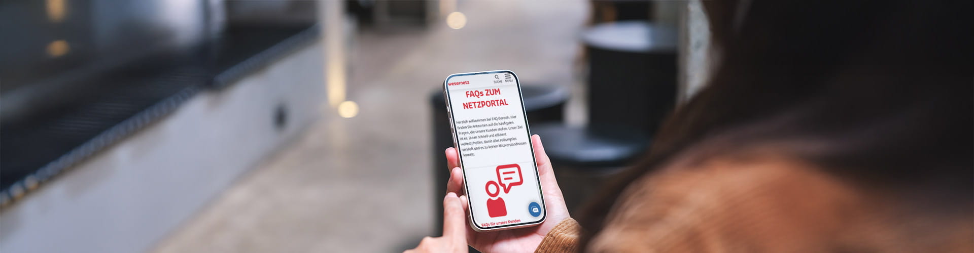 Eine Person liest am Handy die Seite mit FAQs zum Netzportal durch