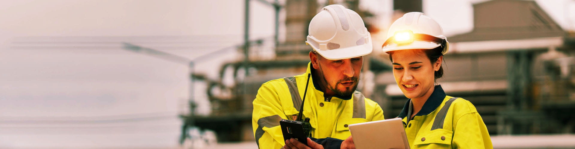 Bauingenieure schauen auf Tablet, Industrieanlage im Hintergrund