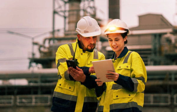 Bauingenieure schauen auf Tablet, Industrieanlage im Hintergrund