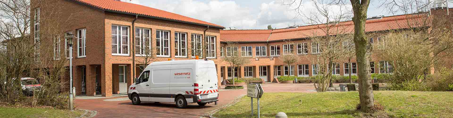 Ein wesernetz Transporter parkt vor einem Backsteingebäude einer Gemeinde