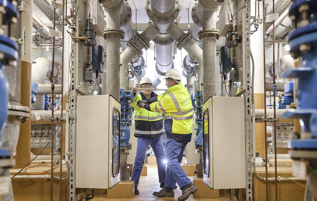 Zwei Mitarbeiter in wesernetz Arbeitskleidung arbeiten in einem Wasserwerk