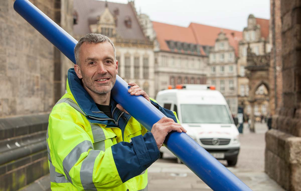 Wesernetz-Mitarbeiter in Schutzjacke trägt blaues Rohr in der Bremer Innenstadt