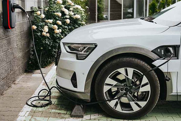 Ein weißes E-Auto lädt an einer Ladestation vor einem Privathaus