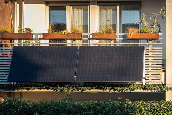 An einem Balkon hängen zwei Solar-Panele