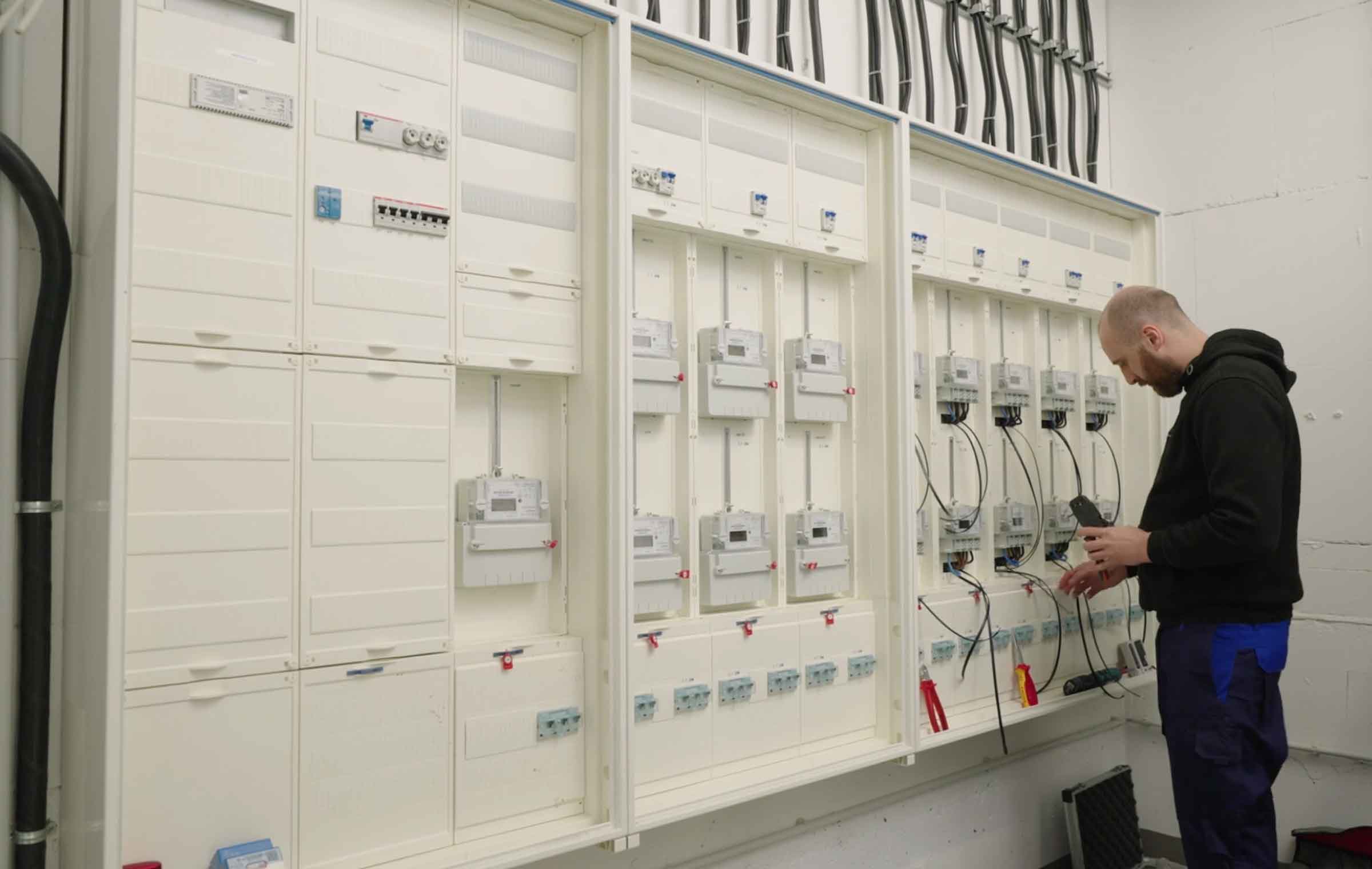 Ein Mitarbeiter wechselt einen Stromzähler. Beim Anklicken des Bildes startet ein Video zu Zählerwechsel.