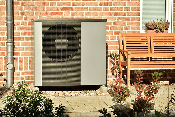 Eine schwarze Wärmepumpe vor einem Backsteinhaus