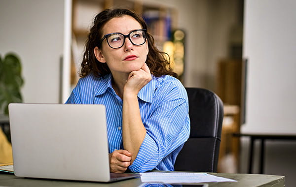 Frau vor einem Laptop überlegt