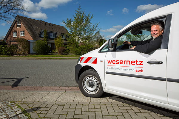 Ein Mitarbeiter lächelt nach erfolgreichem Netzanschluss durch das Fenster seines Autos