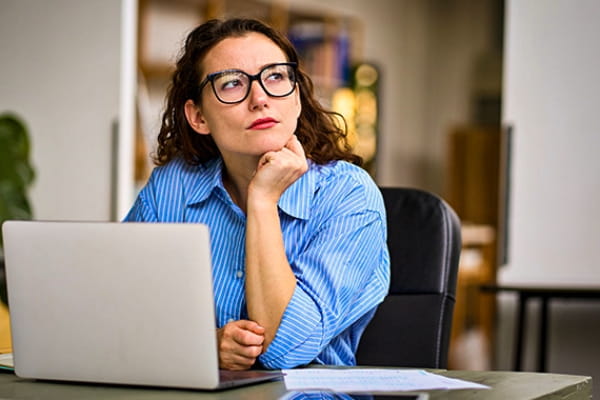 Frau vor einem Laptop überlegt