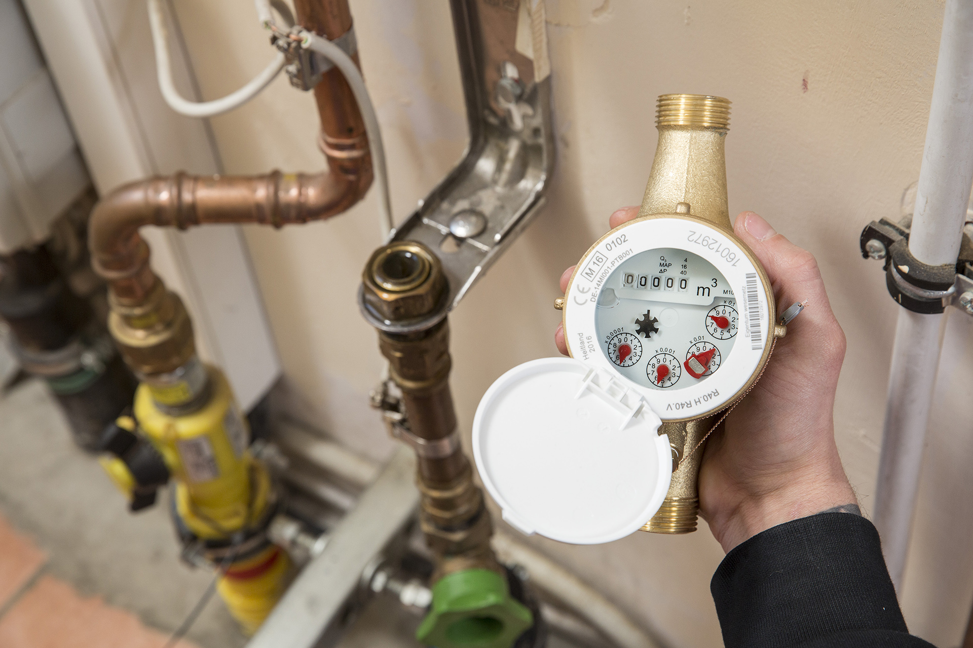 Ein mechanischer Wasserzaehler wird in der Hand gehalten