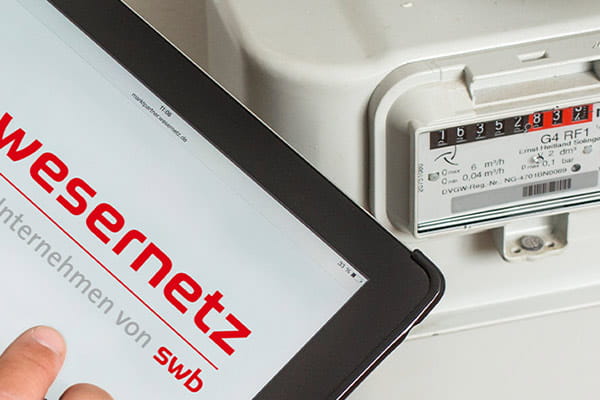 Wesernetz-Webseite zur Zählerstanderfassung im Vordergrund, Stromzähler im Hintergrund sichtbar